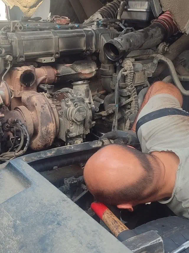 Mechanik pracuje na motoru kamionu za kabinou